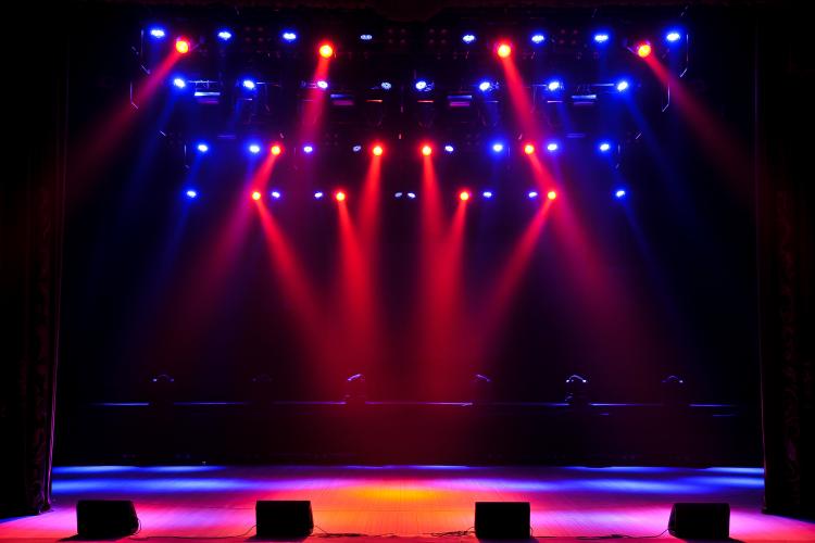 A photo of a stage illuminated by various colors of lights ranging from blue, red, and a light mix between the two.