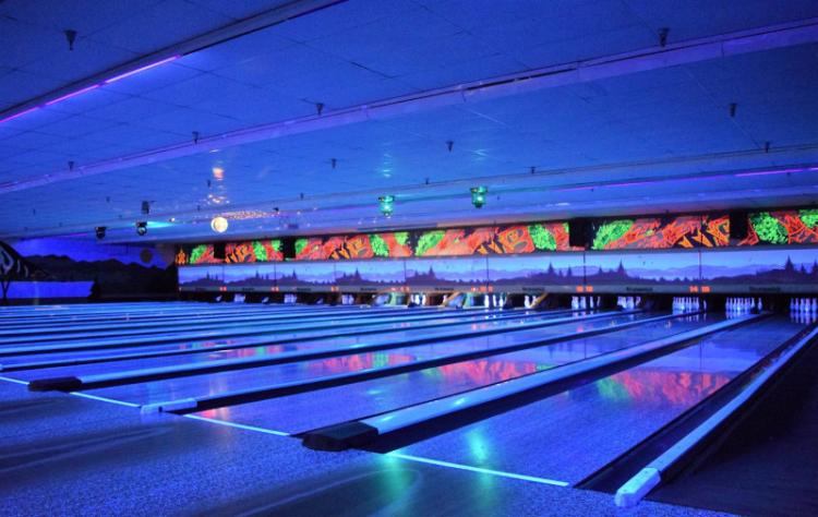 Blue neon lights illuminate the lanes indoors at the Big Bear Bowling Barn during glow bowling events.