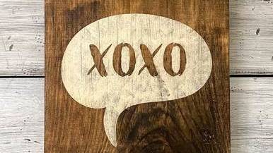 흰색 바탕에 XOXO가 그려진 나무 간판이 놓여 있습니다.