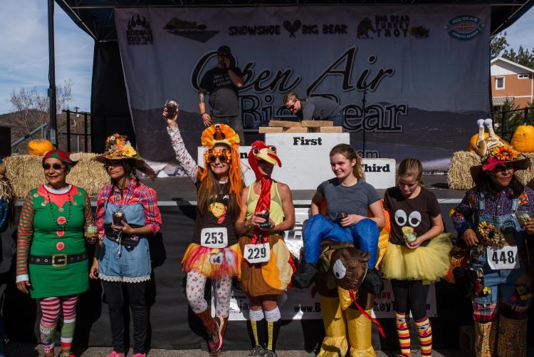 The awards ceremony during the Thanksgiving Turkey Trot, racers are lined up in front of a stage in their costumes.